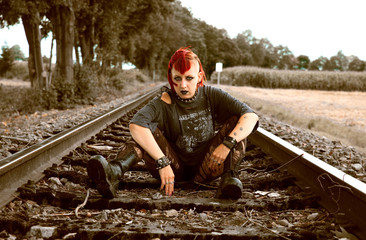 Junge Punk-Frau sitzt auf Schienen 