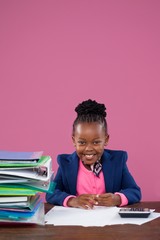 Portrait of smiling businesswoman doing paperwork at desk