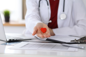 Unknown female doctor with stethoscope holding heart