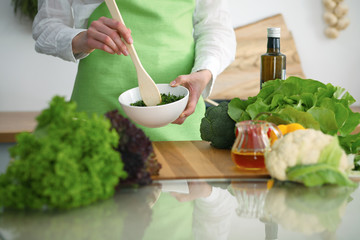 Closeup of human hands cooking vegetables salad in kitchen on the glass  table with reflection