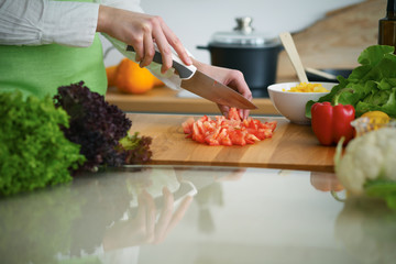 Closeup of human hands cooking vegetables salad in kitchen on the glass  table with reflection