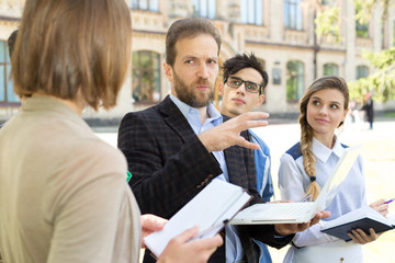 Teacher holds a lesson for a group of students in the open air near the university. Training, introductory lesson.