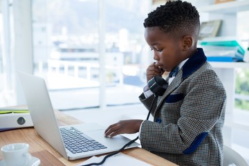 Businessman scrolling on laptop while using telephone