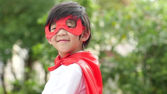 Asian child in in Superhero's costume playing in the park slow motion