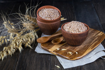Wheat, Oat bran in clay  bowl and ears of wheat and oat.  Dietary supplement to improve digestion....