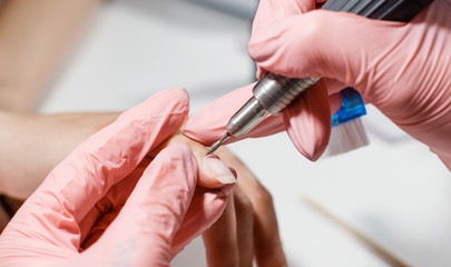 Hardware manicure. Removal of old gel varnish in the salon. Manicure master doing beauty procedure for client, closeup and top view