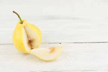 Dissected fresh ripe yellow pear and slice of pear on rustic white old wooden table