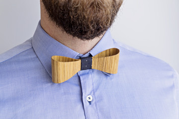 Close Up Portrait of Bearded Adult Man in Blue Shirt and Stylish Wooden Bow Tie. Happy Boss's boss chef day concept selective focus, copy space