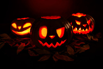 Halloween pumpkin lantern with dry leaves with burning candles