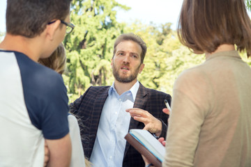 Discussion. Speaker teacher talks with a group of students near the university.