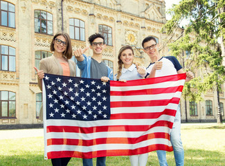 Group of American students holding flag of USA on the university campus. Group four happy people having waving American flag.