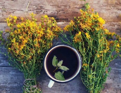 Herbal tea in an old iron cup and St. John's Wort flowers, soft focus. Tea and herbs, alternative medicine