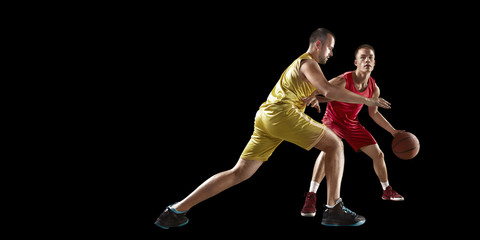 Two basketball players fight for the basketball ball. Isolated basketball players on a black...