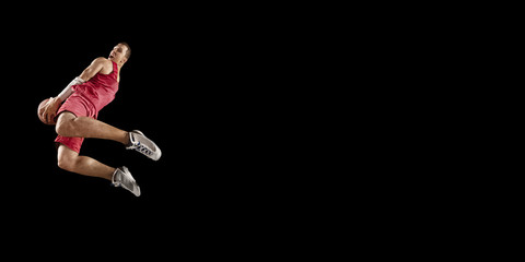Basketball player makes slam dunk. Isolated basketball player on a black background. Player wears...