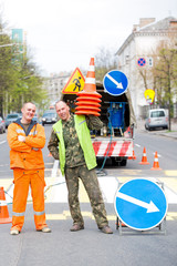 Smiling traffic sign marking technician workers on city street during zebra crossing renovation painting work