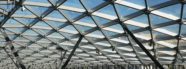 The glass ceiling of the modern building supports a steel beams grid