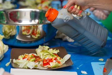 Chef pouring sauce on salad, cooking process, restaurant concept