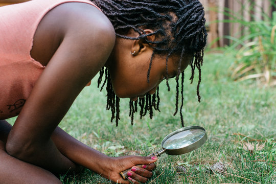 African American girl studying bugs with a magnifying glass