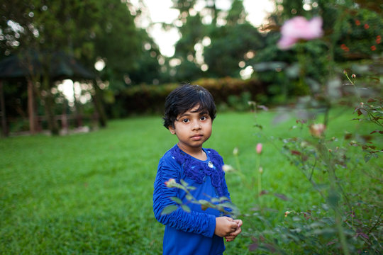 Child with a blank expression looking at camera in the lawn