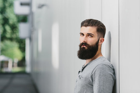 Young man leaning against a gray wall