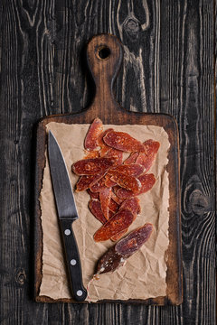 Chorizo and knife on cutting board.Top view/Sliced chorizo and knife on rustic wooden table