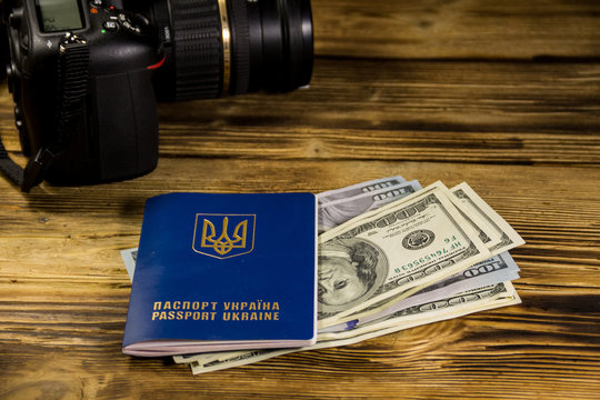 Traveling concept with  ukrainian passport, dollars and modern photo camera on wooden desk
