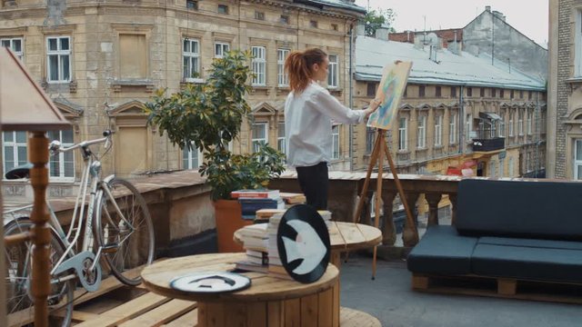 The artist paints a painting on the balcony of the workshop. The old Town. Slow motion. Shot on RED Epic Camera.