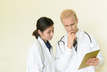 Fototapeta premium caucasian and asian doctor using digital tablet in hospital