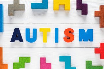 Word Autism built of colorful wooden blocks on wooden background