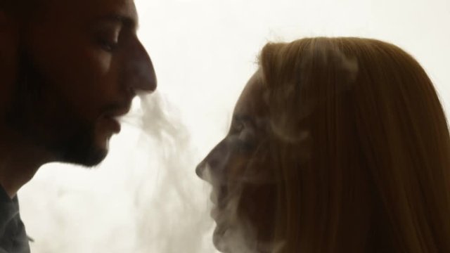 Man gives smoke kiss to woman. Vape culture