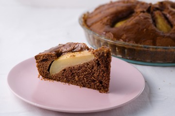 Slice of pear pie on pink plate with whole baked pie in background