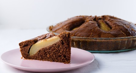 Slice of pear pie on pink plate with whole baked pie in background