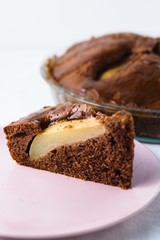 Slice of pear pie on pink plate with whole baked pie in background