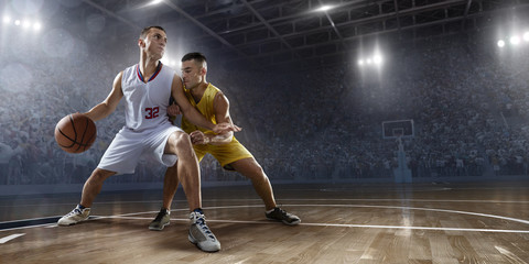 Two basketball players fight for the basketball ball on big professional arena. Player wears...