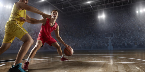 Two basketball players fight for the basketball ball on big professional arena. Player wears...