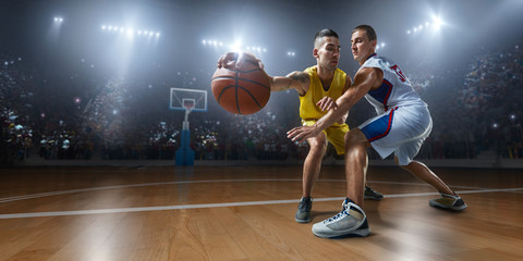 Two basketball players fight for the basketball ball on big professional arena. Player wears...