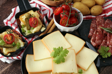 Delicious traditional Swiss melted raclette cheese on diced boiled or baked potato served in individual skillets with salami.