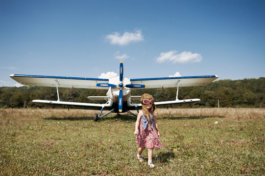 Little girl and propeller biplane airplane