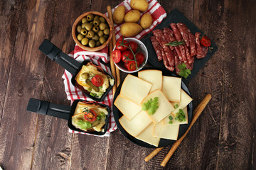 Delicious traditional Swiss melted raclette cheese on diced boiled or baked potato served in...