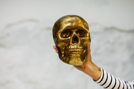 Hand holding a gold skull.