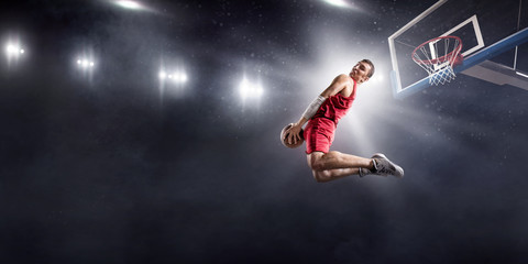 Basketball player makes slam dunk on big professional arena. Player flies through the air with the...