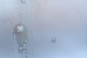 Frosty winter window glass, two thawed spots with snowflakes inside and copy space.