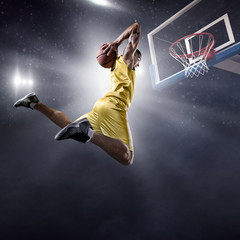 Basketball player makes slam dunk on big professional arena. Player flies through the air with the...