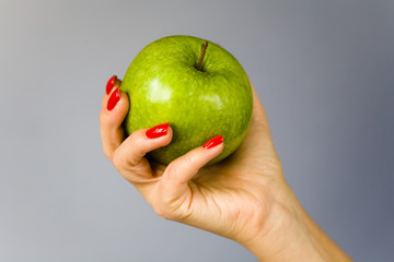 A green apple in a graceful female hand.