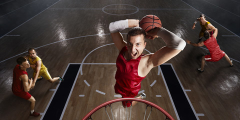 Basketball player makes slam dunk on big professional arena. Player flies through the air with the...