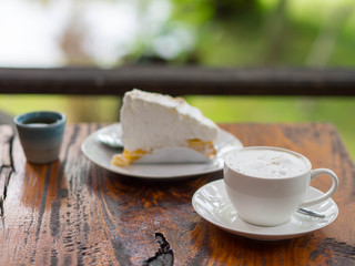Coffee and cake on table with blurred green background