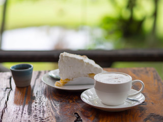 Coffee and cake on table with blurred green background