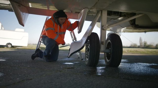  Maintenance engineers looking at blueprint & servicing plane on an airfield