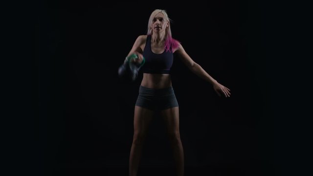  Fit young woman working out with kettle bell weight against black background