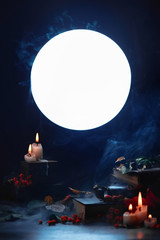 Magical books and candles in a dark still life with full moon. Halloween concept with smoke. Spooky mood.